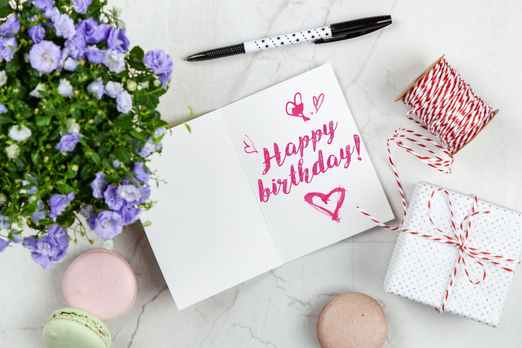 Carte d’anniversaire sur une table en marbre avec des macarons et des fleurs Carte d’anniversaire sur une table en marbre avec des macarons et des fleurs