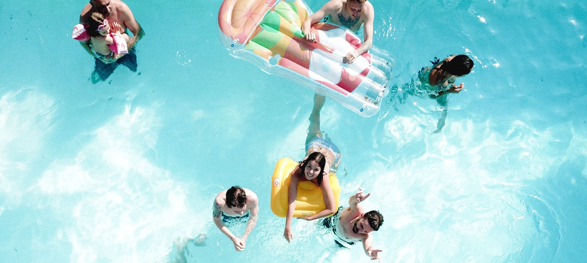 Des personnes qui s’amusent dans une piscine avec des bouées Des personnes qui s’amusent dans une piscine avec des bouées
